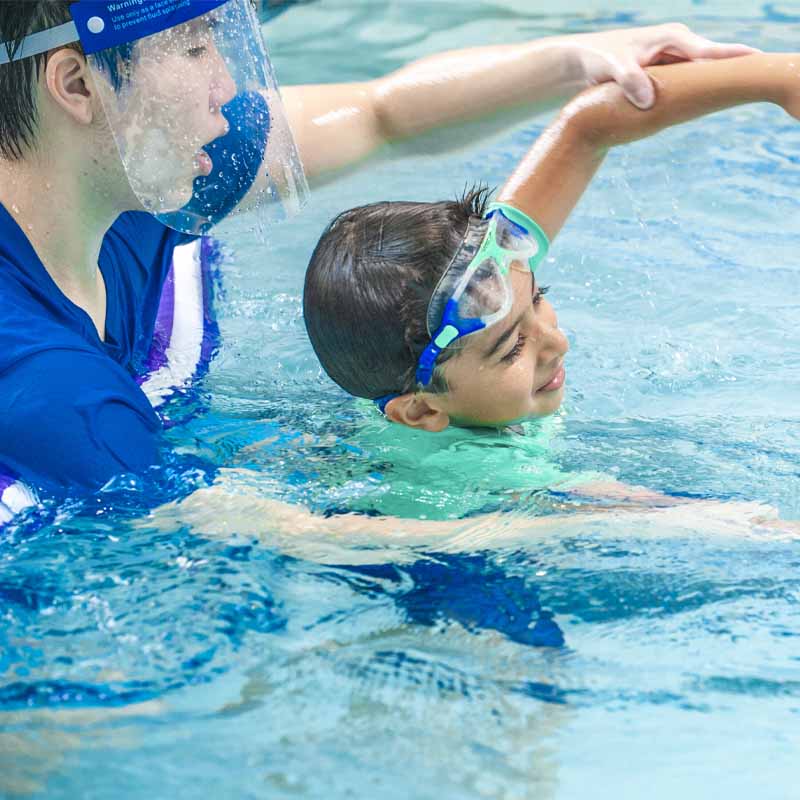 Boy swimming with instructor